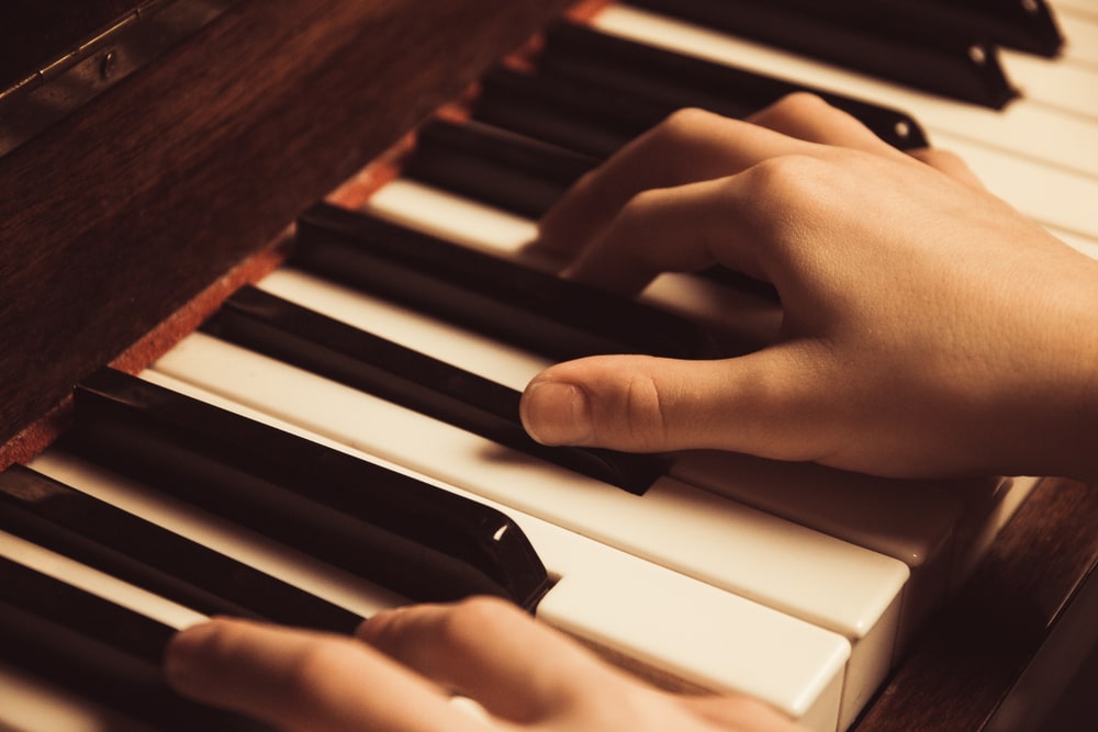 Mani che suonano su pianoforte