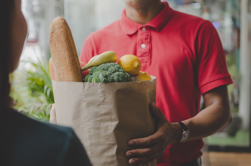 Mani che porgono un pacco di alimenti