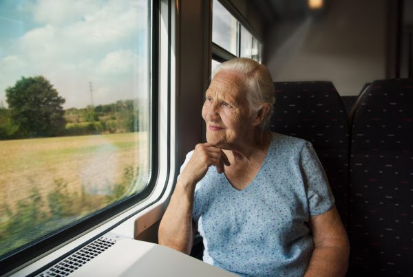 Senior in treno che guarda dal finestrino